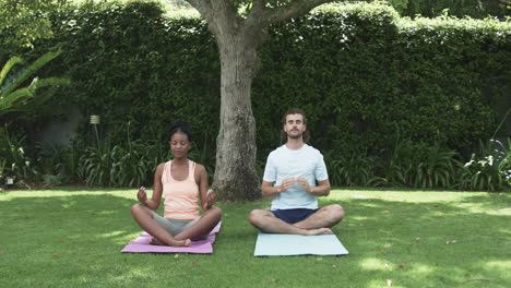 Young-African-American-woman-and-young-Caucasian-man-meditating-outdoors