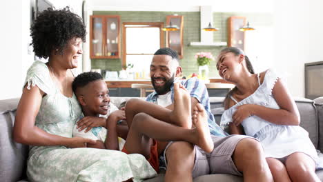 Glückliche-Afroamerikanische-Eltern,-Tochter-Und-Sohn,-Die-Spaß-Auf-Dem-Sofa-Im-Wohnzimmer-Haben,-Zeitlupe