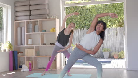 Focused-diverse-fitness-women-exercising-and-practicing-yoga-on-mat-in-white-room,-slow-motion