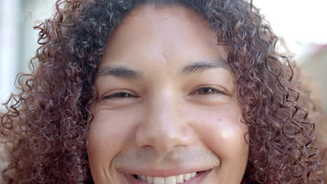 Portrait-close-up-of-eyes-of-happy-biracial-man-with-curly-hair-smiling-in-sunny-garden,-slow-motion