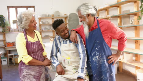 Happy-diverse-group-of-potters-smiling-in-pottery-studio