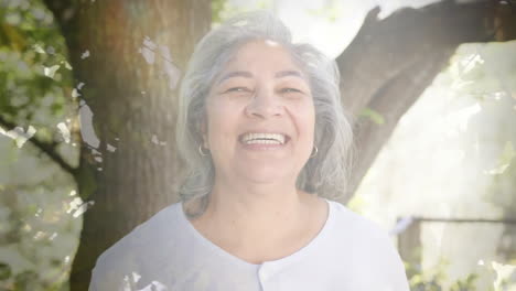 Animación-De-Puntos-De-Luz-Y-árboles-Sobre-Una-Mujer-Birracial-Senior-Sonriente-En-El-Jardín