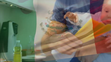 Animation-of-mexican-flag-over-caucasian-father-and-baby-with-food-in-kitchen