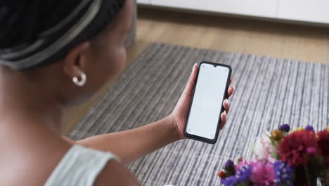 Young-African-American-woman-holds-a-smartphone-at-home,-with-copy-space