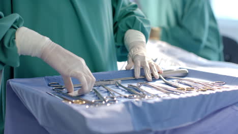 Midsection-of-female-surgeon-preparing-surgical-instruments-in-theatre,-copy-space,-slow-motion