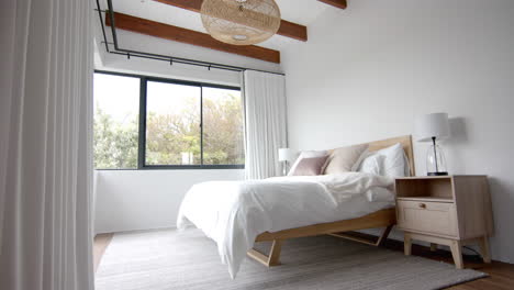 Interior-of-domestic-bedroom-with-double-bed-and-window-overlooking-garden,-copy-space,-slow-motion