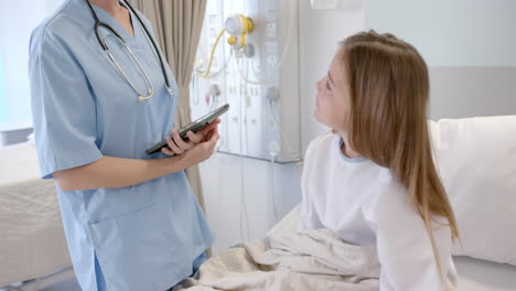 Kaukasische-Ärztin-Mit-Tablet-Im-Gespräch-Mit-Einer-Patientin-Im-Krankenhausbett,-Zeitlupe