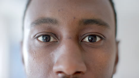 Portrait-close-up-of-eyes-of-african-american-male-doctor-smiling-in-hospital-ward,-slow-motion