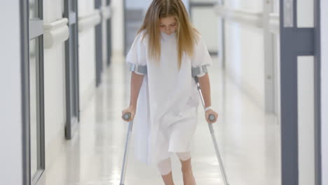 Caucasian-girl-patient-walking-with-crutches-in-hospital-corridor,-slow-motion