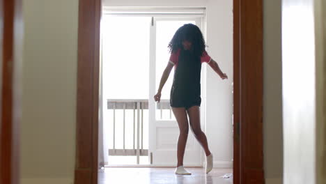 Happy-biracial-woman-playing-and-dancing-at-home,-slow-motion