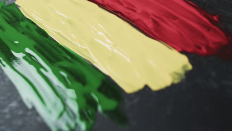Video-of-red,-yellow-and-green-paint-smudges-with-copy-space-on-black-background
