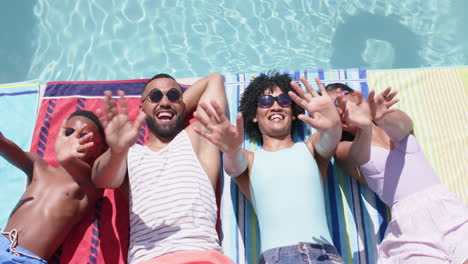 High-angle-of-happy-african-american-parents-and-children-sunbathing-by-pool-waving,-slow-motion