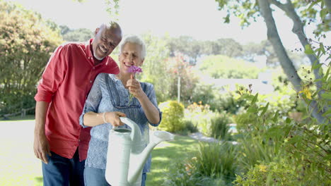 Portrait-of-happy-senior-biracial-couple-embracing-in-sunny-garden-at-home,-slow-motion