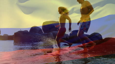 Animation-Der-Kolumbianischen-Flagge-über-Verschiedenen-Freunden,-Die-Am-Sonnigen-Strand-Laufen