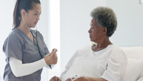 Doctora-Diversa-Examinando-A-Una-Paciente-Anciana-Usando-Estetoscopio-En-La-Habitación-Del-Hospital,-Cámara-Lenta