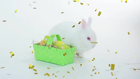 Animation-of-confetti-falling-over-basket-of-easter-eggs-and-rabbit-on-white-background