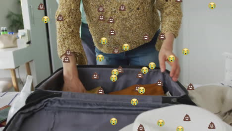 Animation-of-emoji-icons-over-senior-biracial-couple-packing-suitcase