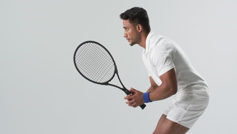 Young-biracial-man-poised-to-hit-a-tennis-ball,-with-copy-space