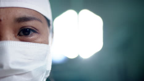 Portrait-of-asian-female-surgeon-wearing-face-mask-in-operating-theatre,-copy-space,-slow-motion
