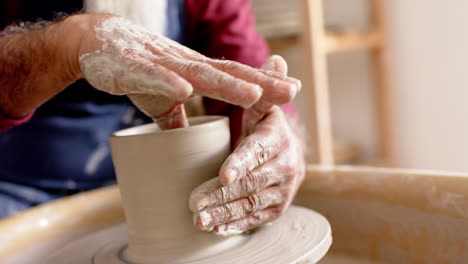 Hands-of-biracial-potter-with-long-beard-working-on-clay-vase-in-pottery-studio,-slow-motion