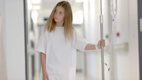 Caucasian-girl-patient-walking-with-drip-stand-in-hospital-corridor,-slow-motion