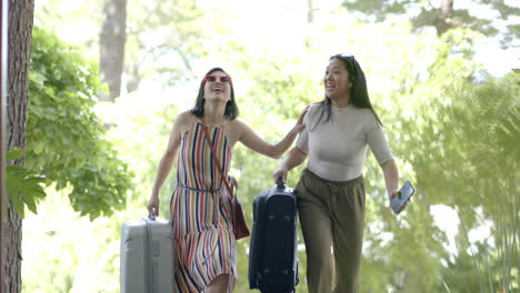 Happy-asian-female-friends-with-suitcases-and-smartphone-walking-on-stairs-of-home,-slow-motion