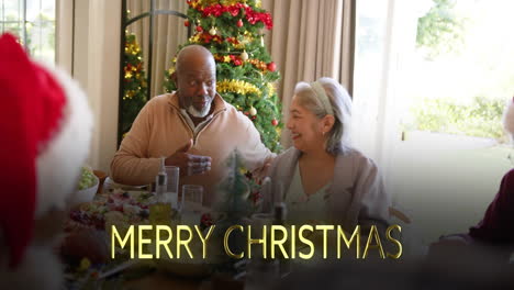 Animation-of-merry-christmas-text-over-diverse-senior-friends-at-christmas-dinner-at-home