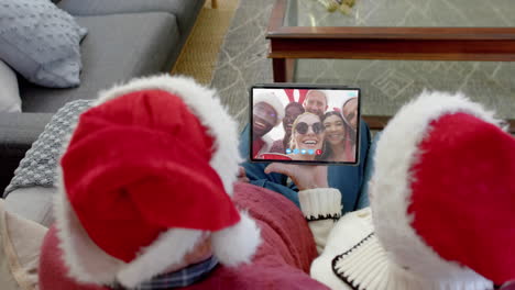 Happy-diverse-couple-and-group-of-friends-having-christmas-tablet-video-call,-slow-motion