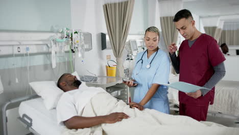 Diverse-doctors-and-male-patient-talking-in-hospital-room,-slow-motion