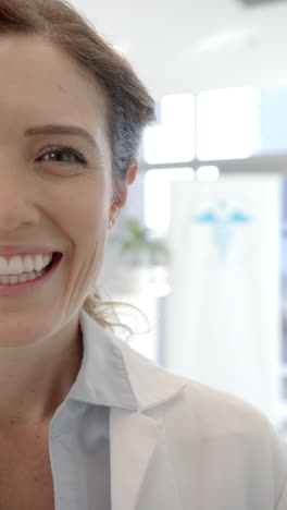 Vertical-video-half-portrait-of-happy-caucasian-female-doctor-at-hospital,-slow-motion,-copy-space