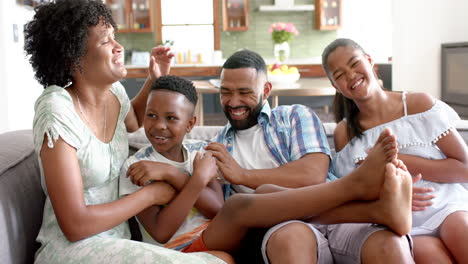 Happy-african-american-parents,-daughter-and-son-having-fun-on-sofa-in-living-room,-slow-motion