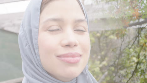 Animation-of-leaves-over-biracial-woman-in-hijab-smiling