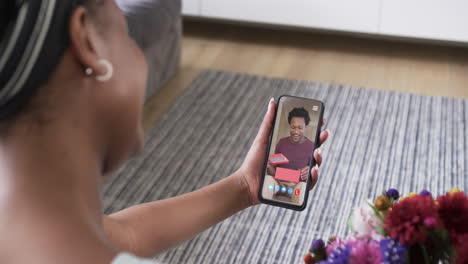 African-american-woman-holding-smartphone-with-african-emerican-man-with-gift-on-screen
