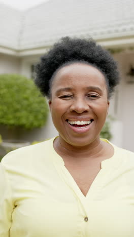 Glückliche-Afroamerikanische-Seniorin,-Die-Vor-Dem-Haus-Steht-Und-Lächelt,-Zeitlupe