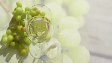 Composite-of-glass-of-white-wine-over-white-grapes-on-wooden-surface