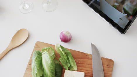 Vegetables,-cheese,-knife,-chopping-board-and-tablet-on-kitchen-worktop,-copy-space,-slow-motion