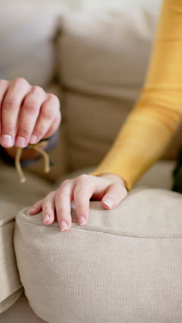 Vertical-video-of-diverse-couple-sitting-on-sofa-and-holding-hands-at-home,-in-slow-motion