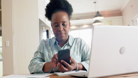 Glückliche-Afroamerikanische-Seniorin-Mit-Laptop-Und-Smartphone-Im-Sonnigen-Zimmer-Zu-Hause,-Zeitlupe