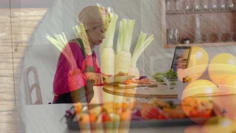 Biracial-woman-in-hijab-chopping-vegetables-in-kitchen,-cooking-over-vegetables