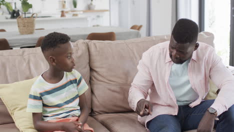 African-American-father-and-son-sit-together-on-a-couch-at-home