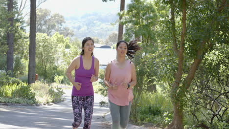 Happy-asian-female-friends-running-near-forest-on-sunny-day,-slow-motion