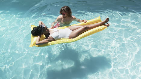 Diverse-couple,-a-young-African-American-woman-and-a-young-Caucasian-man,-enjoy-a-pool-day