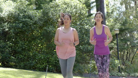 Happy-asian-female-friends-running-near-forest-on-sunny-day,-slow-motion