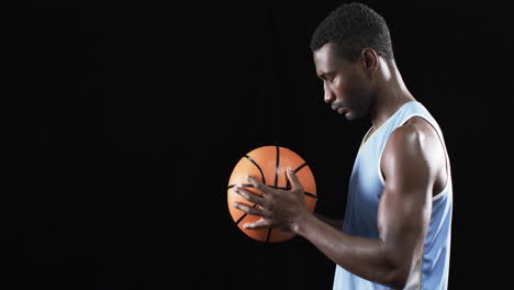 Afroamerikanischer-Mann-Konzentriert-Sich-Auf-Einen-Basketball,-Mit-Kopierraum-Auf-Schwarzem-Hintergrund