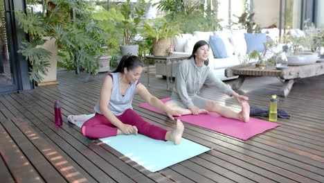 Happy-asian-female-friends-stretching-and-smiling-on-sunny-terrace,-slow-motion