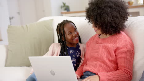 Happy-african-american-mother-with-daughter-using-laptop-at-home,-slow-motion