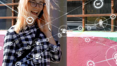 Animation-of-network-of-connected-icons-in-circles-over-happy-caucasian-woman-using-smartphone