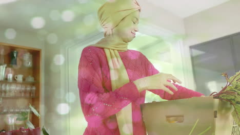 Mujer-Birracial-Con-Hijab-Sacando-Verduras-De-La-Caja-En-La-Cocina-Sobre-Puntos-De-Luz