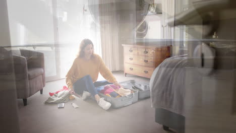 Animation-of-happy-caucasian-woman-packing-suitcase-in-bedroom-over-travellers-wheeling-suitcases