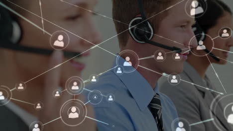 Animation-of-network-of-people-icons-over-caucasian-colleagues-working-with-computers-and-headsets